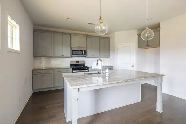 a kitchen with kitchen island granite countertop stainless steel appliances a microwave a sink and a stove