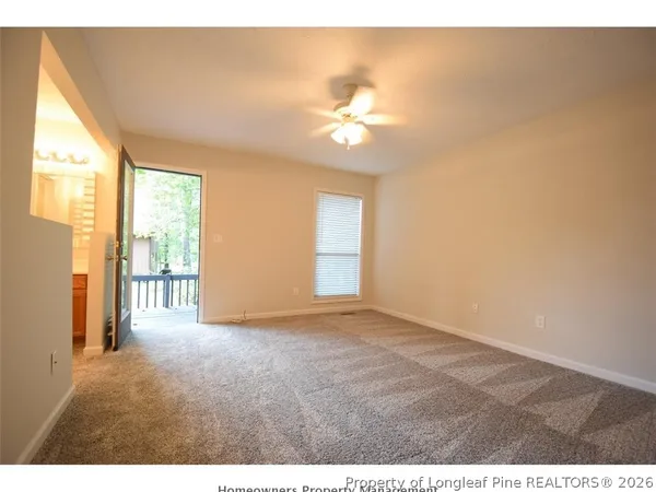 a view of an empty room with chandelier fan and a window