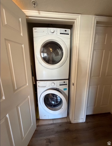 72 300 North, Unit 302 Provo, UT 84601 - Photo 12 of 16 Dedicated laundry closet featuring a stacked white front-loading washer and dryer, tile flooring within the closet, and wood-finish flooring extending into the room