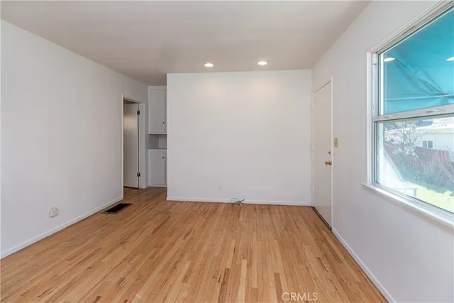 a view of an empty room with wooden floor and a window