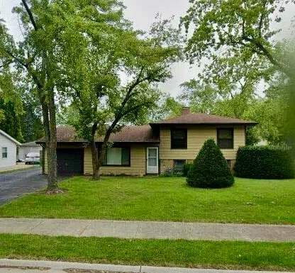 a view of a house with a yard and a large tree