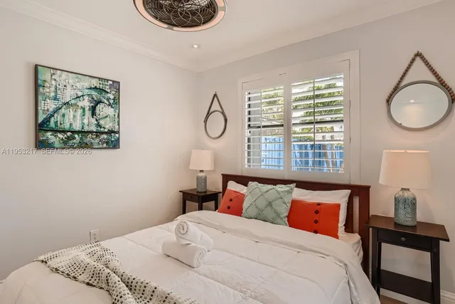 a bedroom with a bed a dresser and a large window