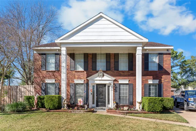 a view of a white house with large windows and plants