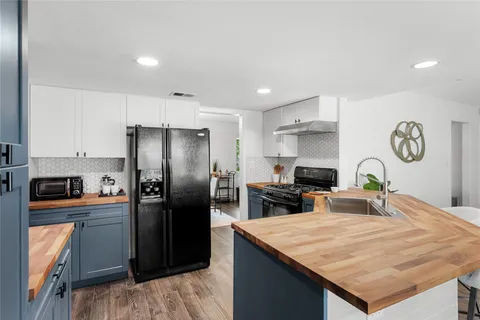 a kitchen with stainless steel appliances granite countertop a refrigerator a stove and a sink with wooden floor