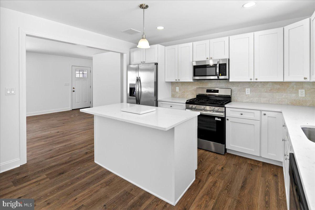 464 Sykesville Road Wrightstown, NJ 08562 - Photo 10 of 32 a kitchen with stainless steel appliances kitchen island granite countertop a stove a sink and white cabinets with wooden floor