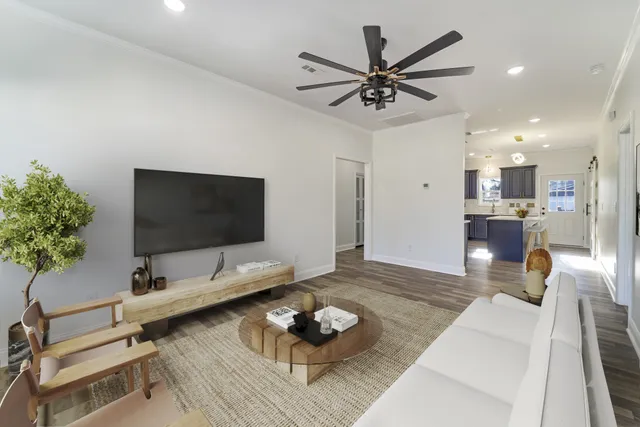 a living room with furniture and a flat screen tv with kitchen view