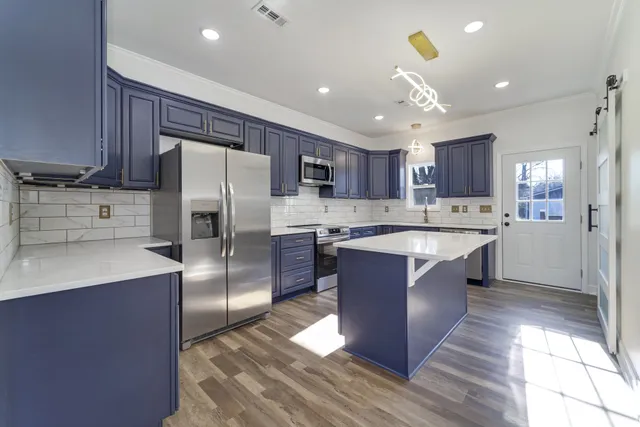 a large kitchen with stainless steel appliances kitchen island granite countertop a refrigerator and a sink