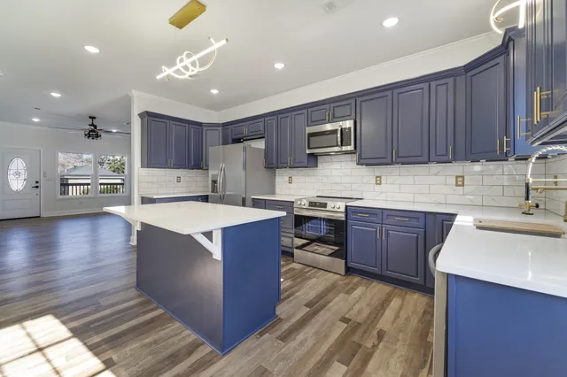 a kitchen with kitchen island granite countertop a sink dishwasher stove and cabinets with wooden floor