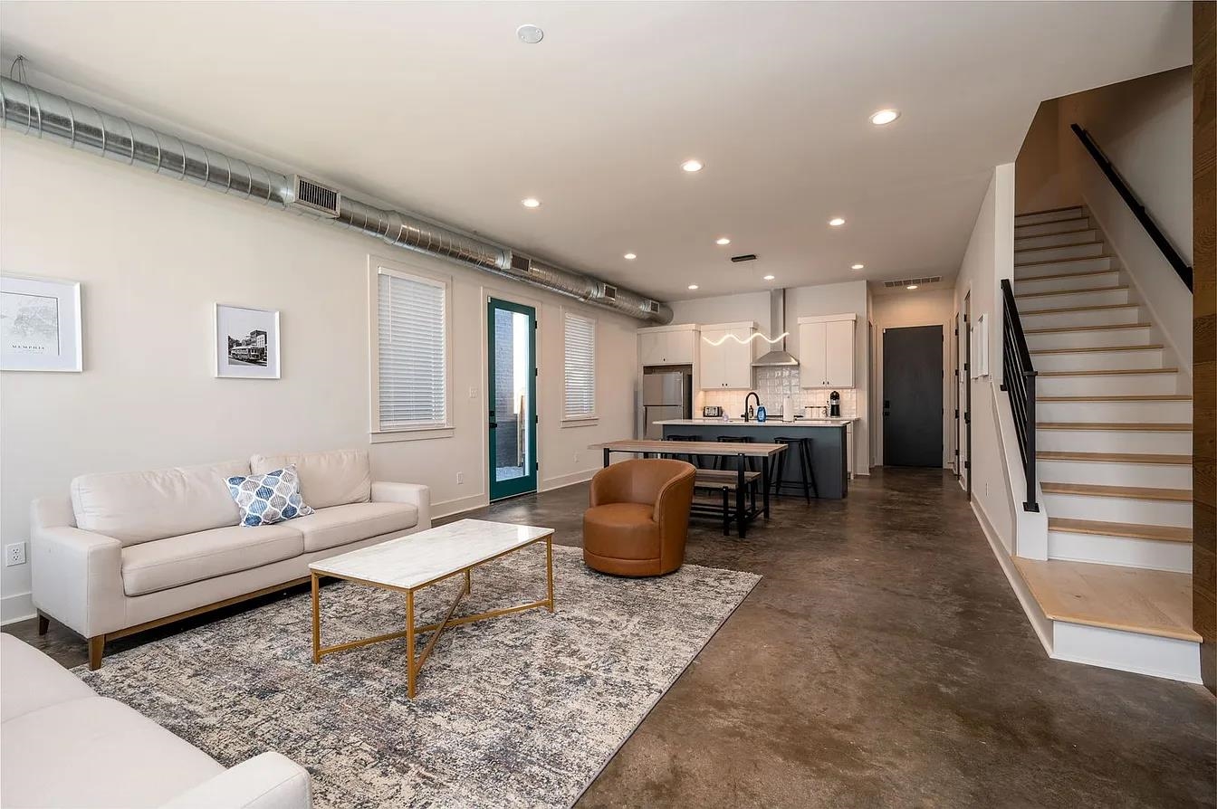 752 Meda Street Memphis, TN 38104 - Photo 3 of 18 Open-concept living area featuring a kitchen island with seating, exposed spiral ductwork, wood-finish flooring on the staircase, and recessed lighting