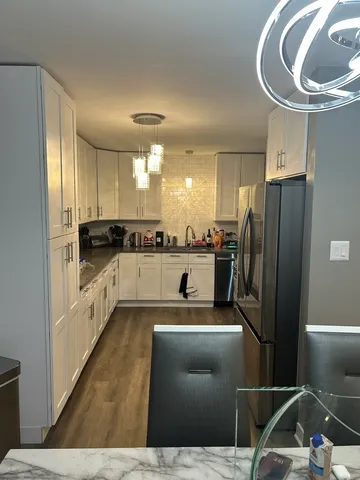 a kitchen with stainless steel appliances kitchen island granite countertop a refrigerator and a sink