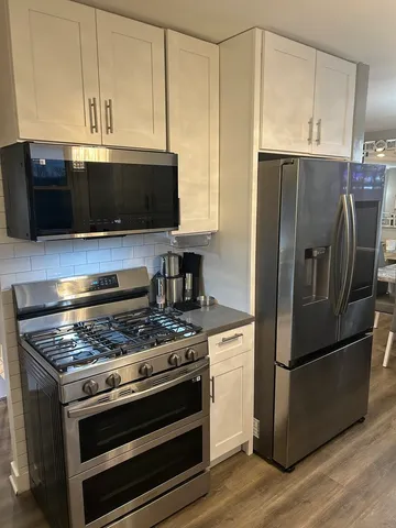 a kitchen with granite countertop a refrigerator stove and microwave