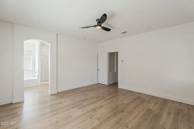 a view of empty room with wooden floor and fan