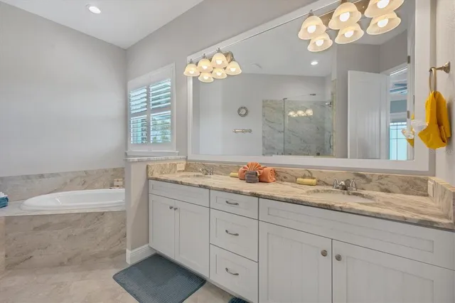 a bathroom with a granite countertop sink a large mirror a bathtub and next to a window
