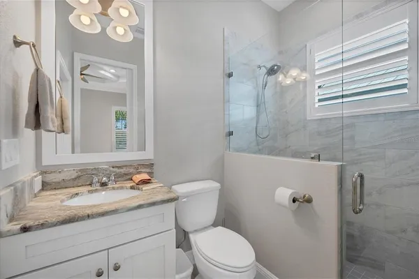 a bathroom with a granite countertop sink toilet a mirror and shower
