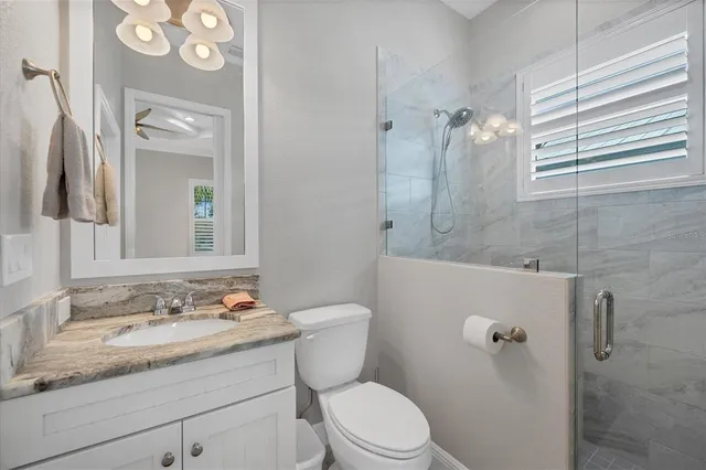 a bathroom with a granite countertop sink toilet a mirror and shower