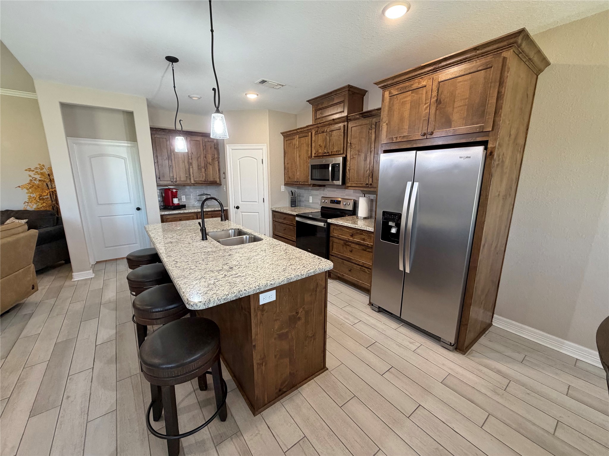 216 Shannon Street Angleton, TX 77515 - Photo 5 of 26 a kitchen with kitchen island a counter top space a refrigerator a stove a chimney and a dining table with wooden floor
