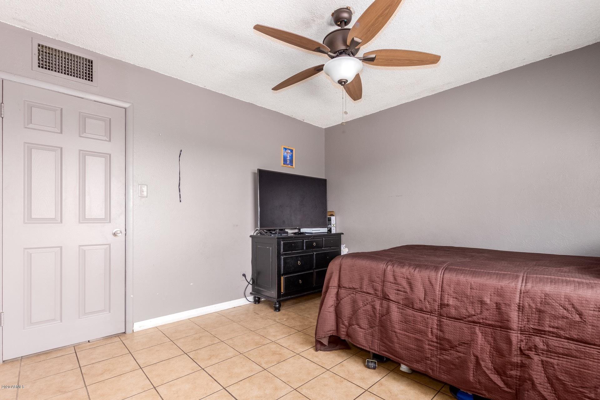 7019 West Camelback Road Phoenix, AZ 85033 - Photo 11 of 25 a bedroom with a bed and a chandelier