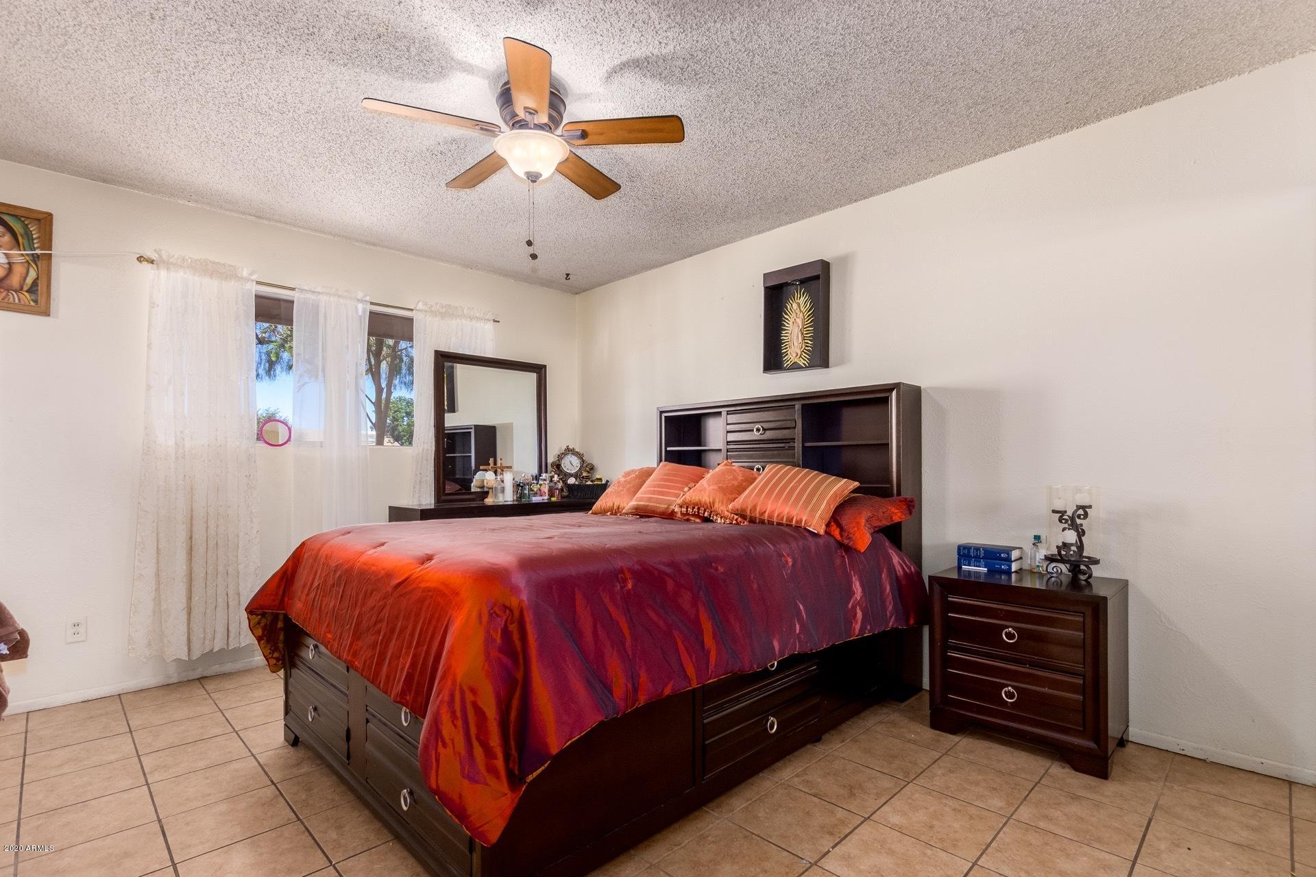 7019 West Camelback Road Phoenix, AZ 85033 - Photo 9 of 25 a bedroom with a bed and a chandelier