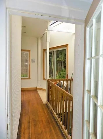 a view of a hallway with wooden floor and windows