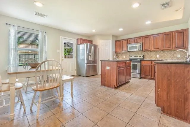 a kitchen with stainless steel appliances granite countertop a stove a sink a microwave a dining table and chairs