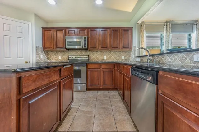 a kitchen with stainless steel appliances granite countertop wooden cabinets a stove top oven a sink and dishwasher