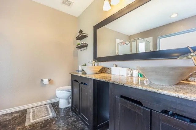 a bathroom with a granite countertop toilet sink and mirror