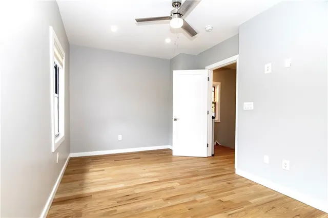 a view of a hallway with wooden floor and a bathroom
