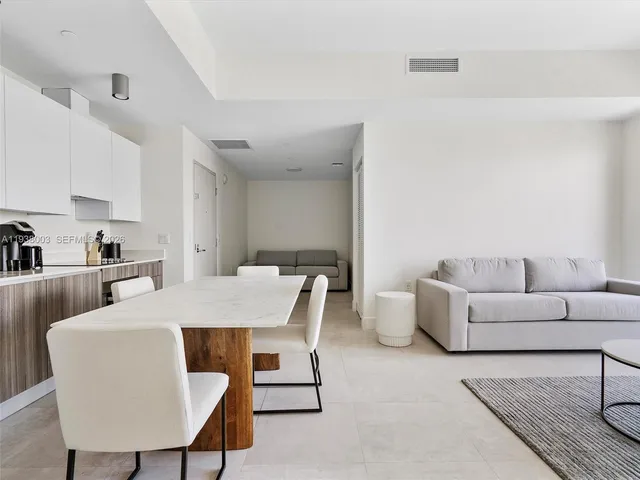 a living room with furniture a rug and a kitchen