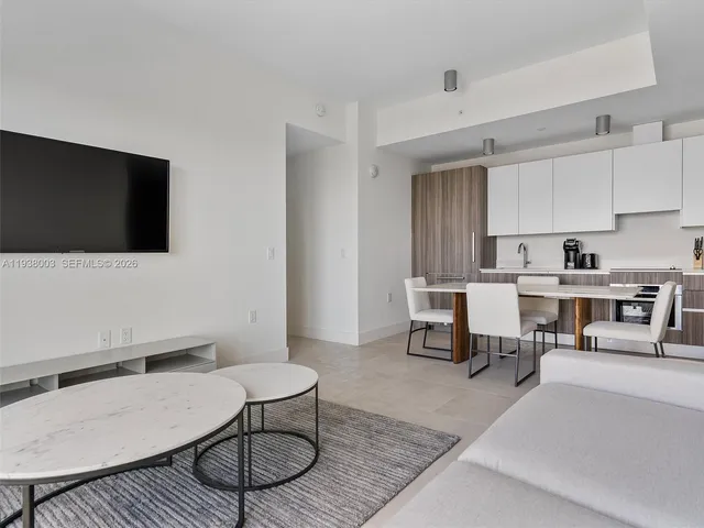a living room with furniture a flat screen tv and kitchen view