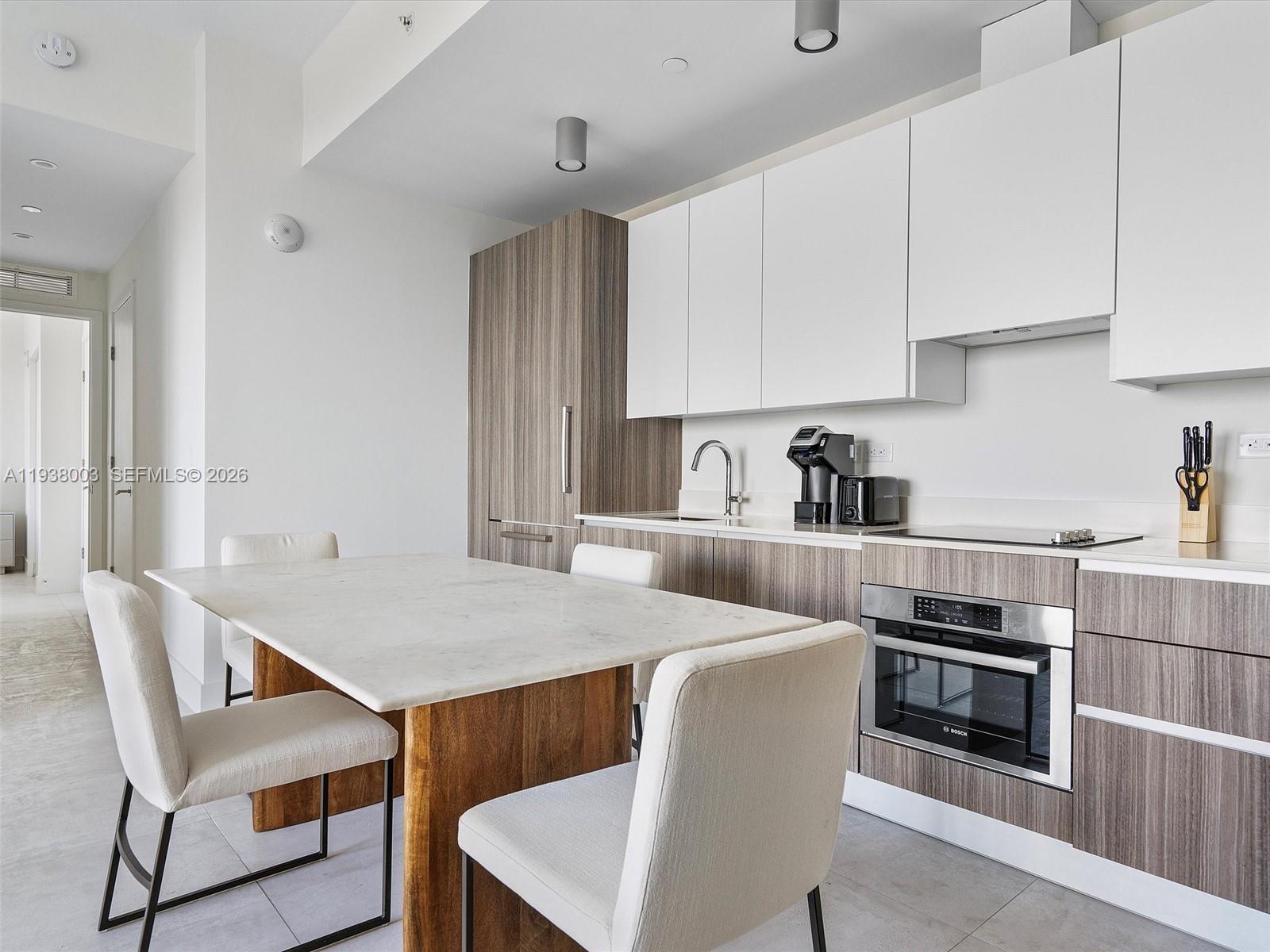 239 Southwest 9th Street, Unit 2003 Miami, FL 33130 - Photo 25 of 52 a kitchen with stainless steel appliances granite countertop a stove a refrigerator a sink a dining table and chairs with wooden floor