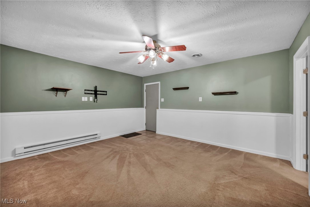 47655 Cooper Foster Park Road Amherst, OH 44001 - Photo 27 of 49 Empty room featuring baseboard heating, ceiling fan, a textured ceiling, and carpet