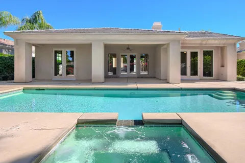 a view of a white house with a big yard and potted plants