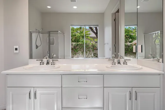 a bathroom with double vanity sink a mirror and a window