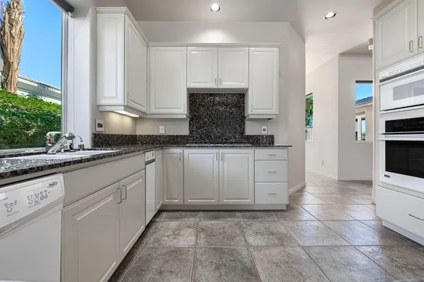 a kitchen with granite countertop a sink stainless steel appliances and cabinets