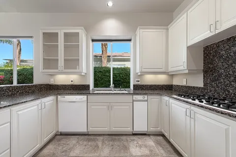 a kitchen with granite countertop a sink and white cabinets