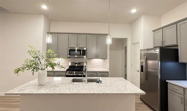 a kitchen with stainless steel appliances kitchen island granite countertop a stove a sink a microwave and cabinets