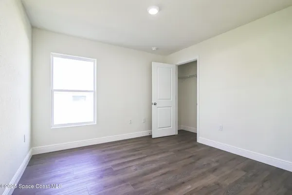 an empty room with wooden floor and window