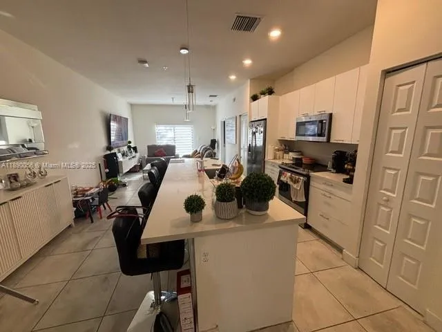 a view of kitchen with kitchen island stainless steel appliances sink stove microwave and cabinets