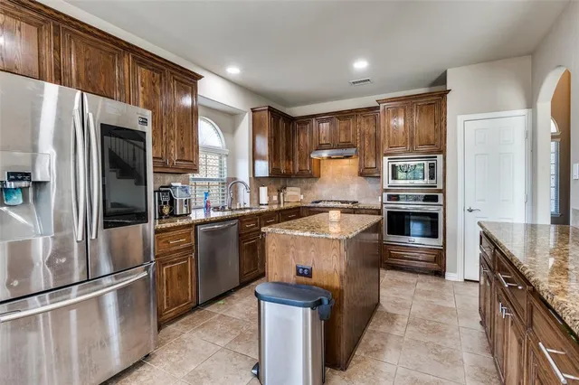 a kitchen with stainless steel appliances granite countertop a refrigerator a stove and a sink