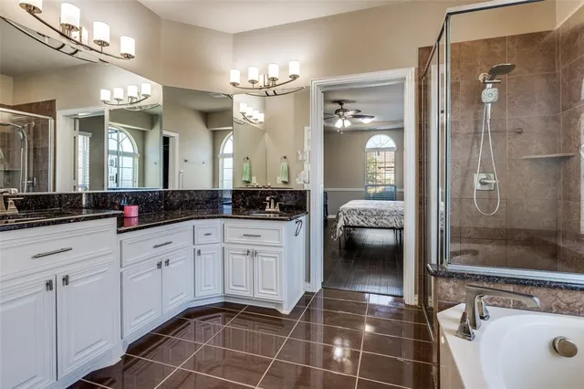 a en suite bathroom with a granite countertop sink a toilet a mirror and shower