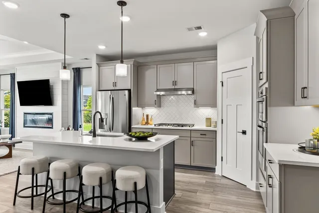 a kitchen with stainless steel appliances granite countertop a stove top oven a refrigerator a sink and chairs