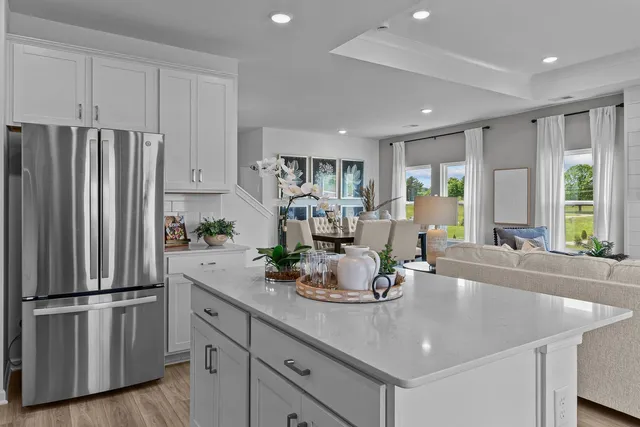 a kitchen with stainless steel appliances granite countertop a refrigerator a sink a stove and white cabinets with wooden floor