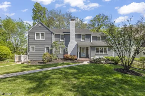 a front view of a house with a yard and trees