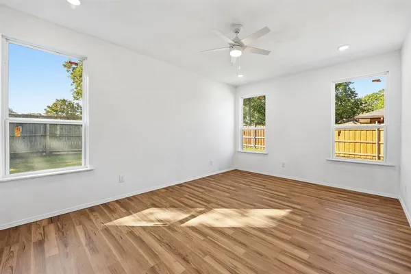 a view of an empty room with window and wooden floor