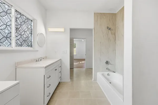 a spacious bathroom with a tub sink and mirror