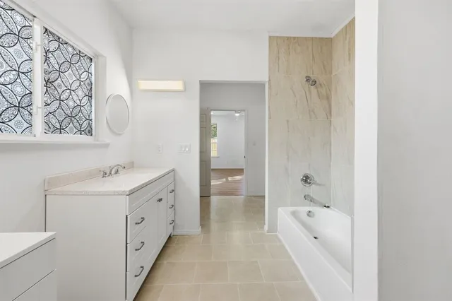 a spacious bathroom with a tub sink and mirror