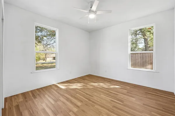 a view of empty room with wooden floor and fan