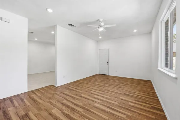 an empty room with windows and ceiling fan