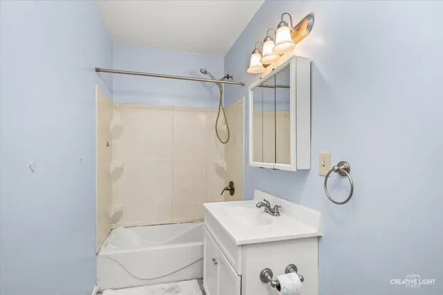 a bathroom with a sink a light fixture and a shower
