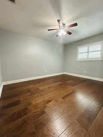 an empty room with wooden floor and windows with curtains
